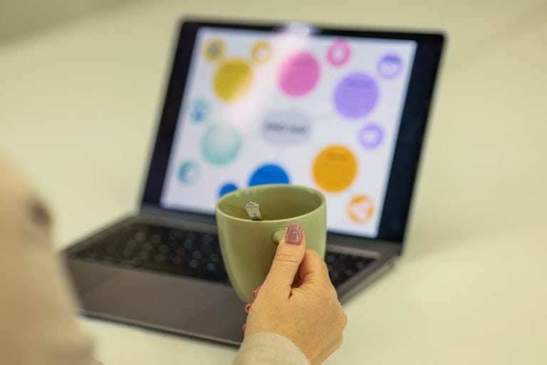 Woman is relaxing with coffee while looking at a laptop.