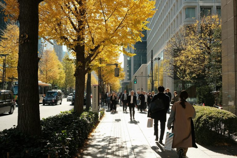 A group of people walking down a street next to tall buildings