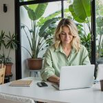 Woman works on her laptop at a bright, green space.